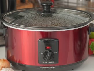 slow cooking -- a crockpot on a counter with some garlic, onions, and brocoli