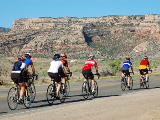 Group Riding Culture -- group of cyclists with a rocky desert plateau in the background