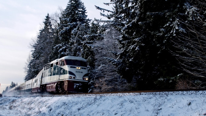 Training to Ski -- Am image of an Amtrak train with snow and pine trees